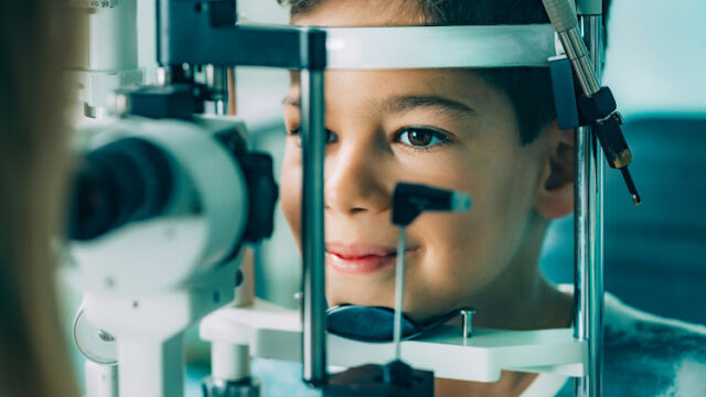 Eye Exam. Ophthalmologist examining boy’s eyes with slit lamp